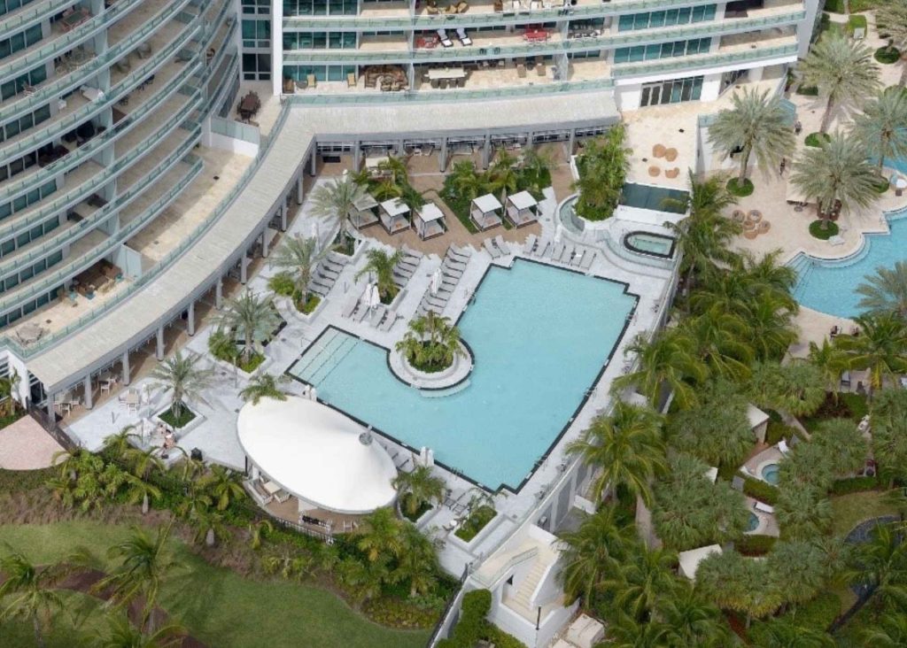 An l-shaped pool with greenery all around.